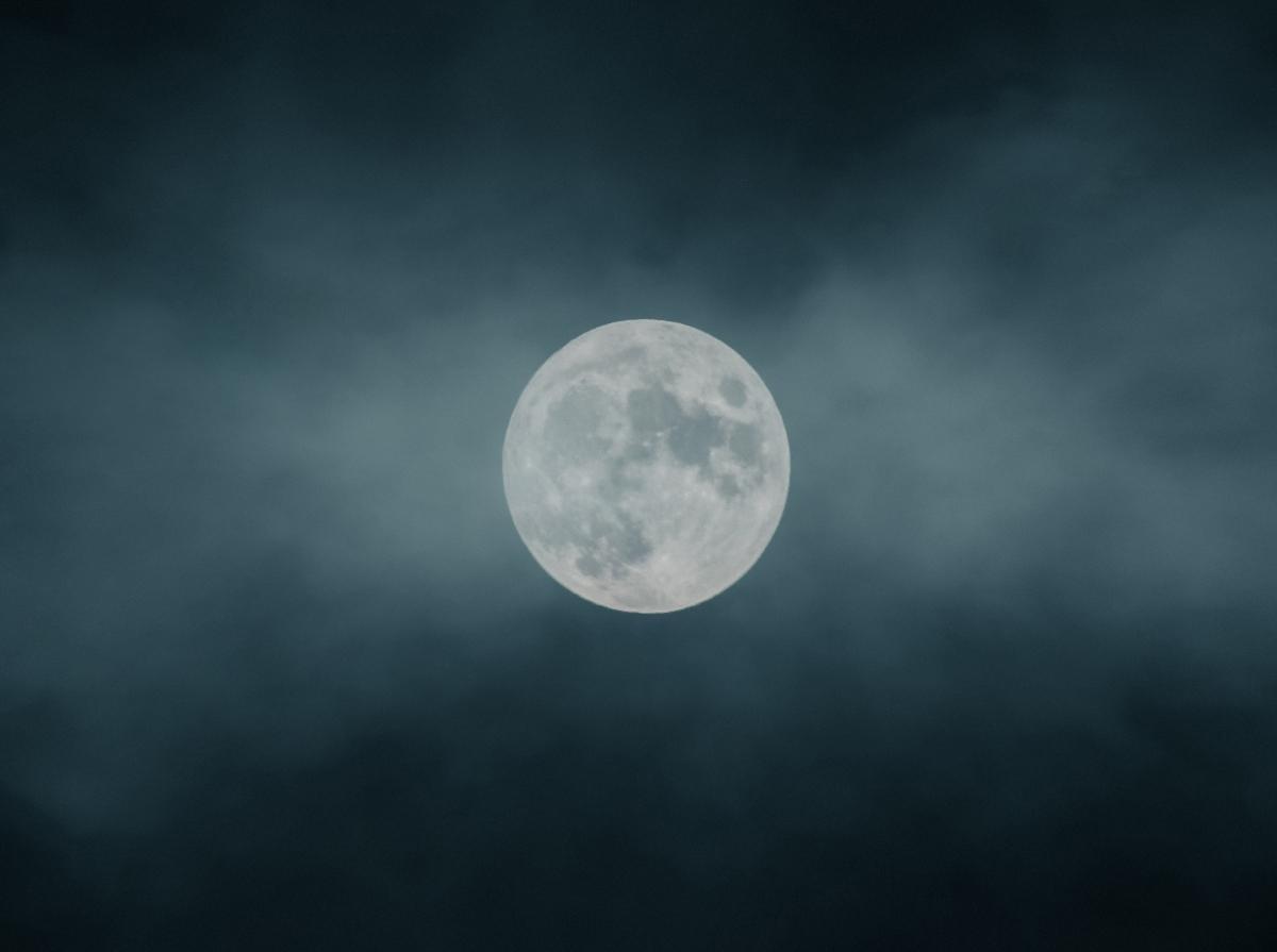 Full moon in a hazy gray sky.