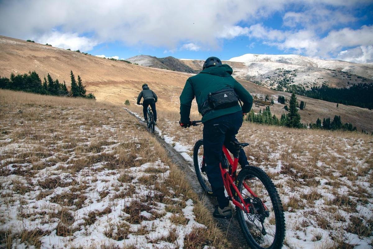 two people riding uphill on slightly snowy trails