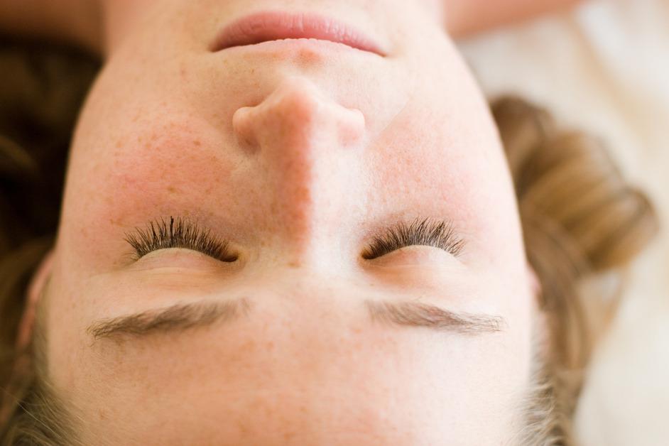 A close-up and upside-down view of a woman's face with her eyes closed. 