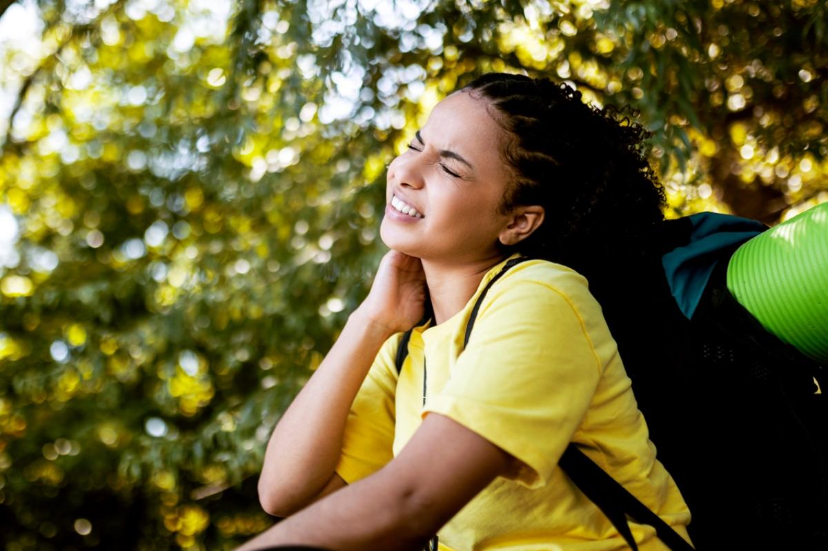 Young woman in yellow shirt rubbing mosquito bites