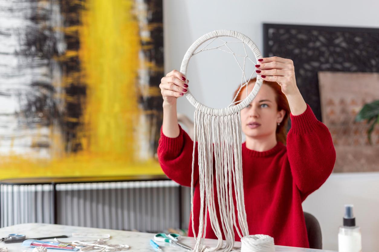 Person holding up a half-finished macrame dreamcatcher.