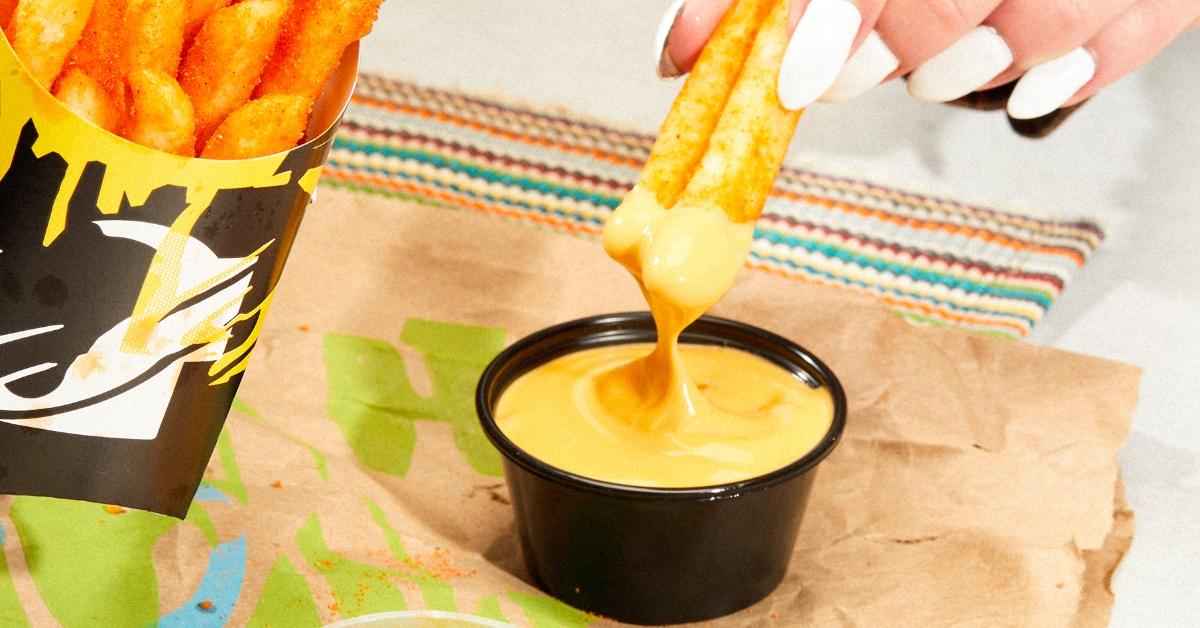 Taco Bell Nacho Fries being dipped in Vegan Nacho Sauce. 