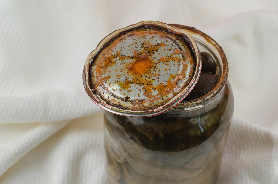 Jar of food with opened lid revealing rust under the surface. 