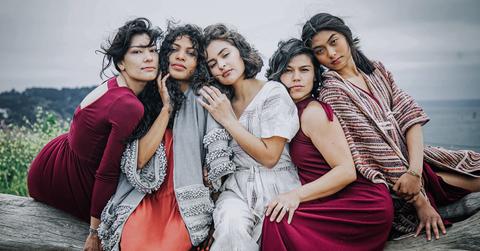 Five women wearing red-hued outfits pose for the camera.