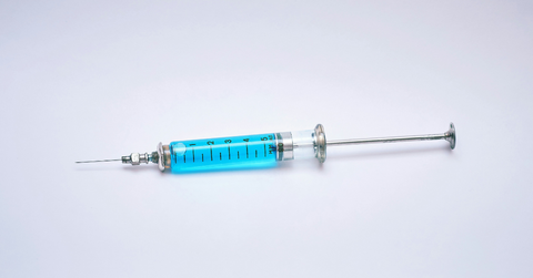 A syringe holds blue liquid