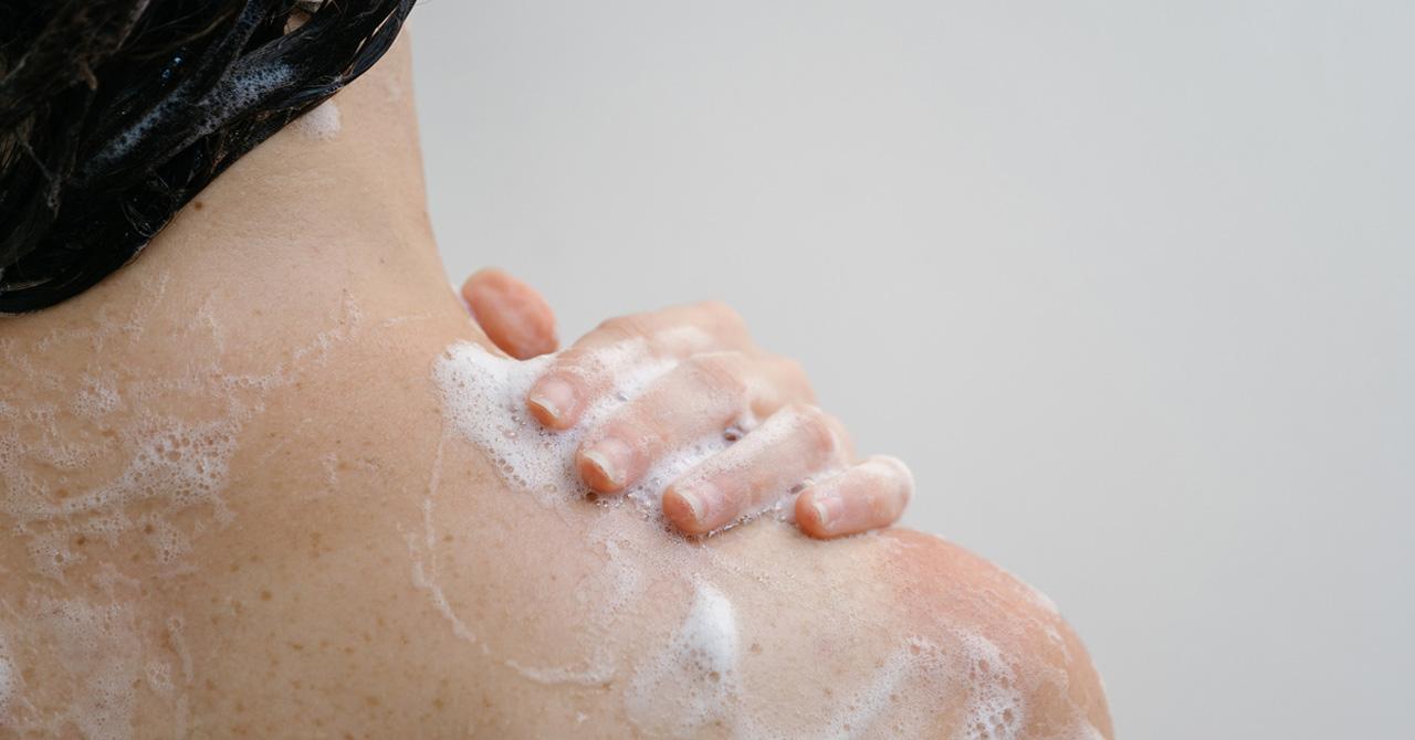 woman taking shower with body wash