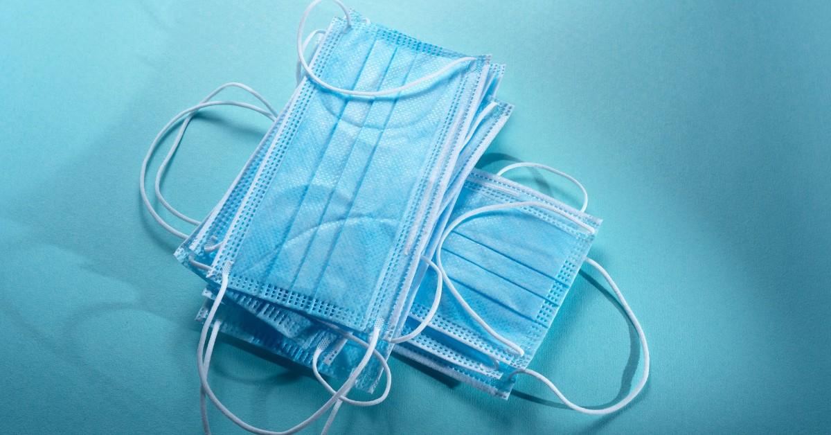 A pile of blue facemasks sit on a desk