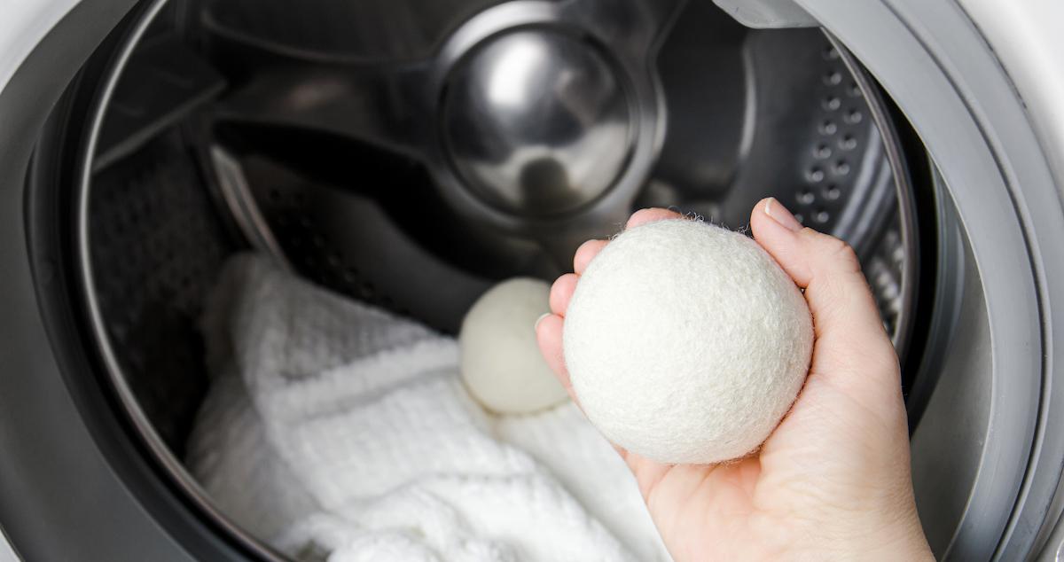 Hand holds a white dryer ball in front of a dryer