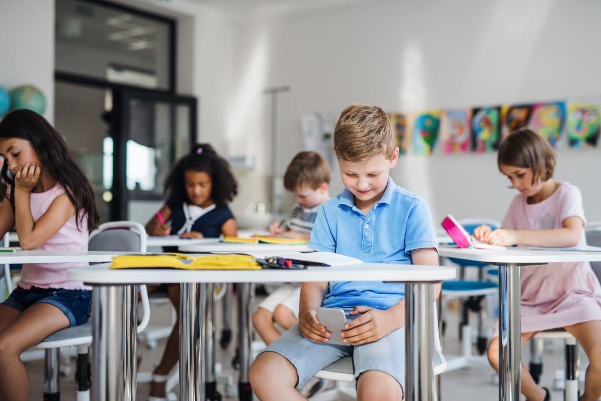 Child distracted and unable to focus in the classroom by his phone. 