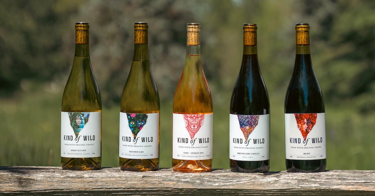 Five wine bottles of Kind of Wild Wines on a wooden surface with greenery in blurred background