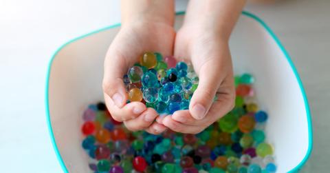 Child's hands hold water beads over bowl