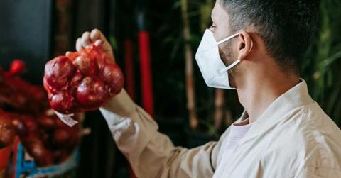A man wearing a mask looks at a bag of onions. (Representative Cover Image Source: Pexels | Michael Burrows)