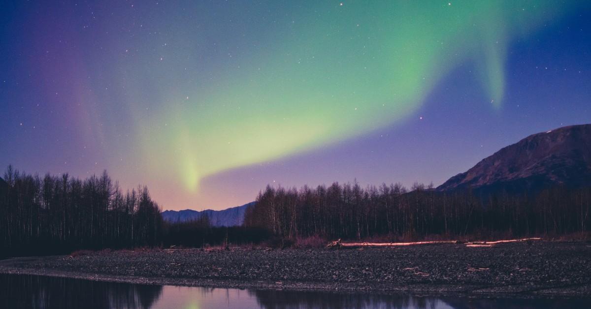 The northern lights appear pink, yellow, purple, and green