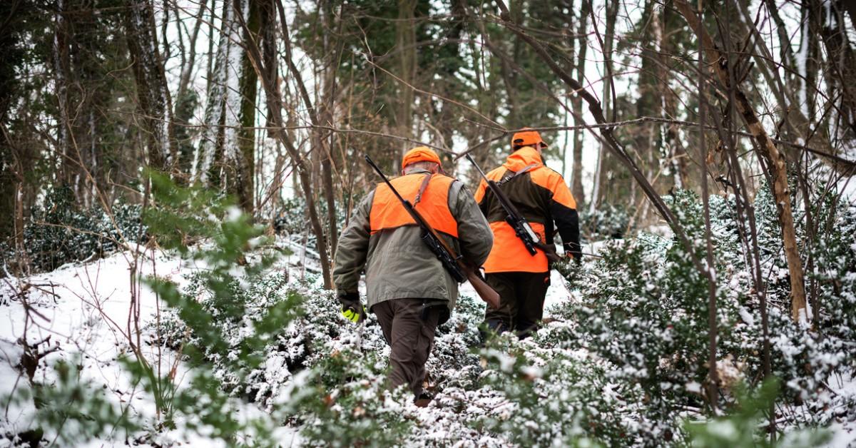 Two deer hunters head into the snowy woods