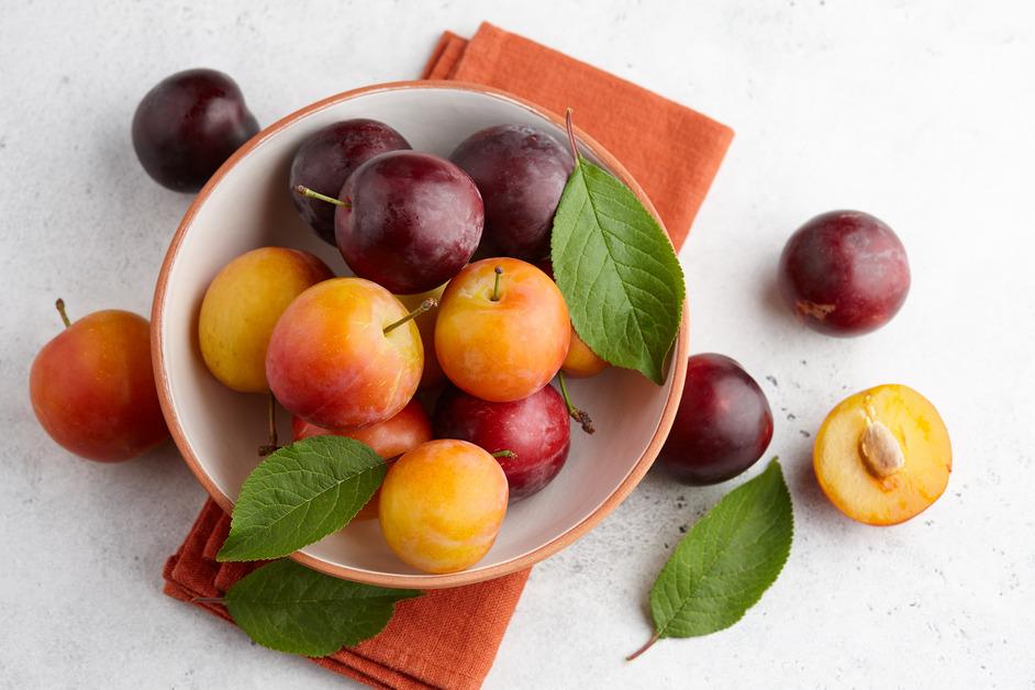 A bowl filled with peaches, plums and nectarines. 