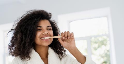 woman brushing teeth with bamboo toothbrush