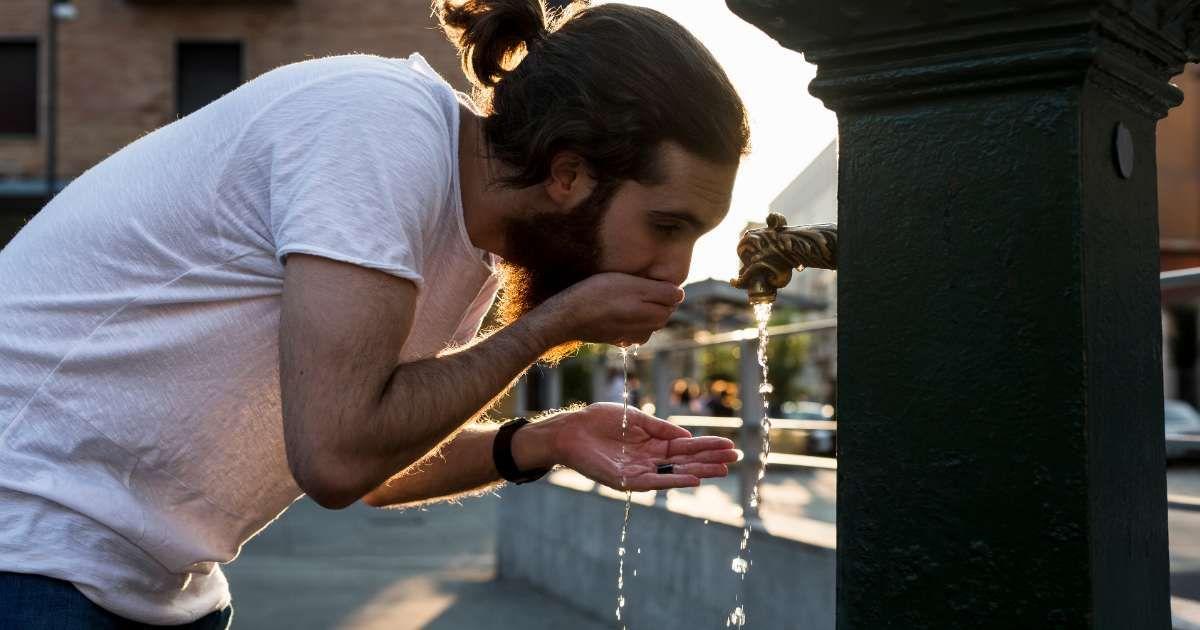 A young man is drinking from a public water tap in a city. (Representative Cover Image Source: Getty Images | Westend61)