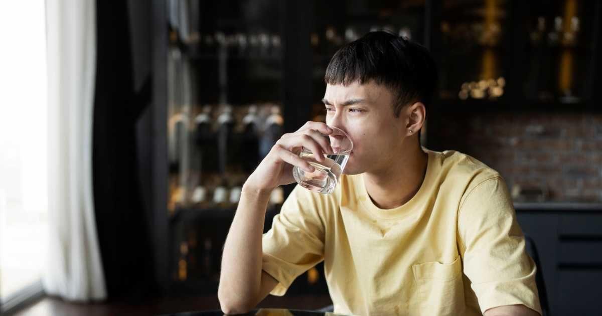 A man scrunches his face while drinking water from a glass. (Representative Cover Image Source: Freepik)