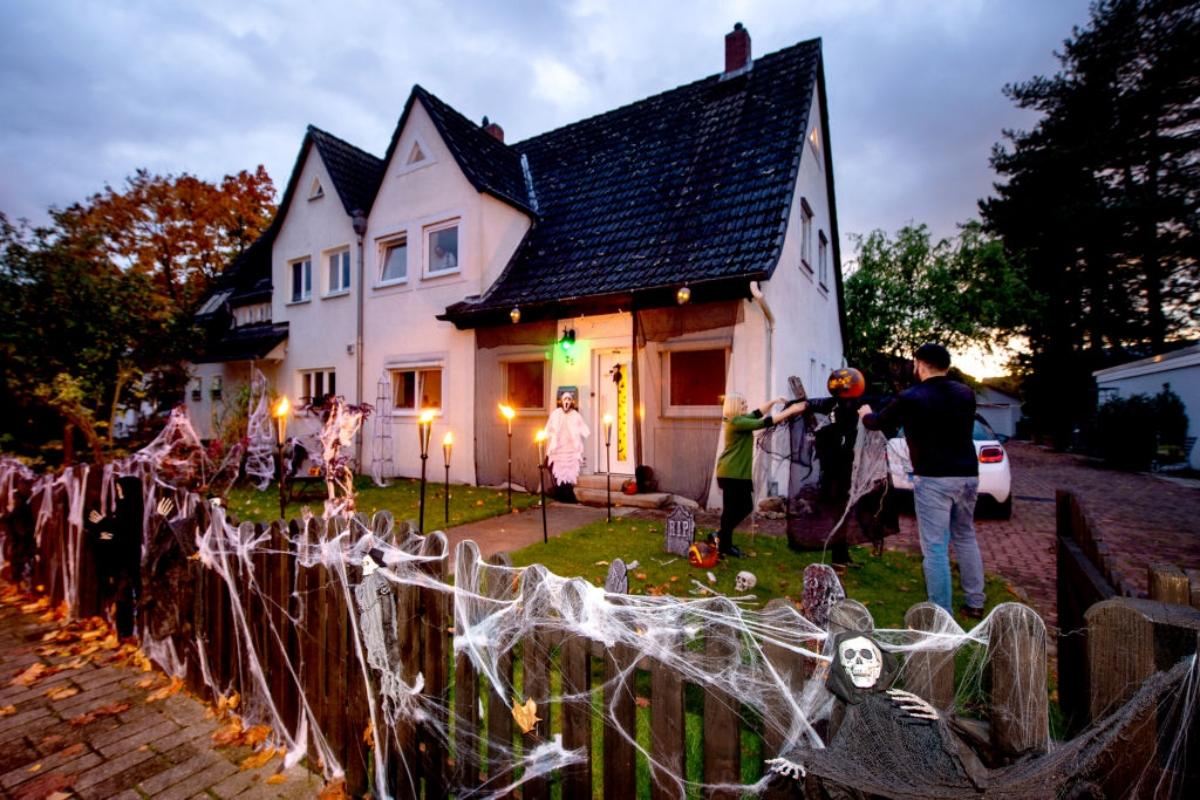 A couple decorates their yard with fake spider webs and other items.