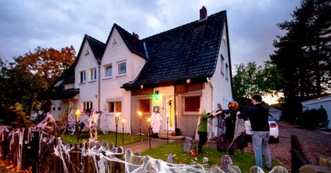 A couple decorates their yard with fake spider webs and other items.