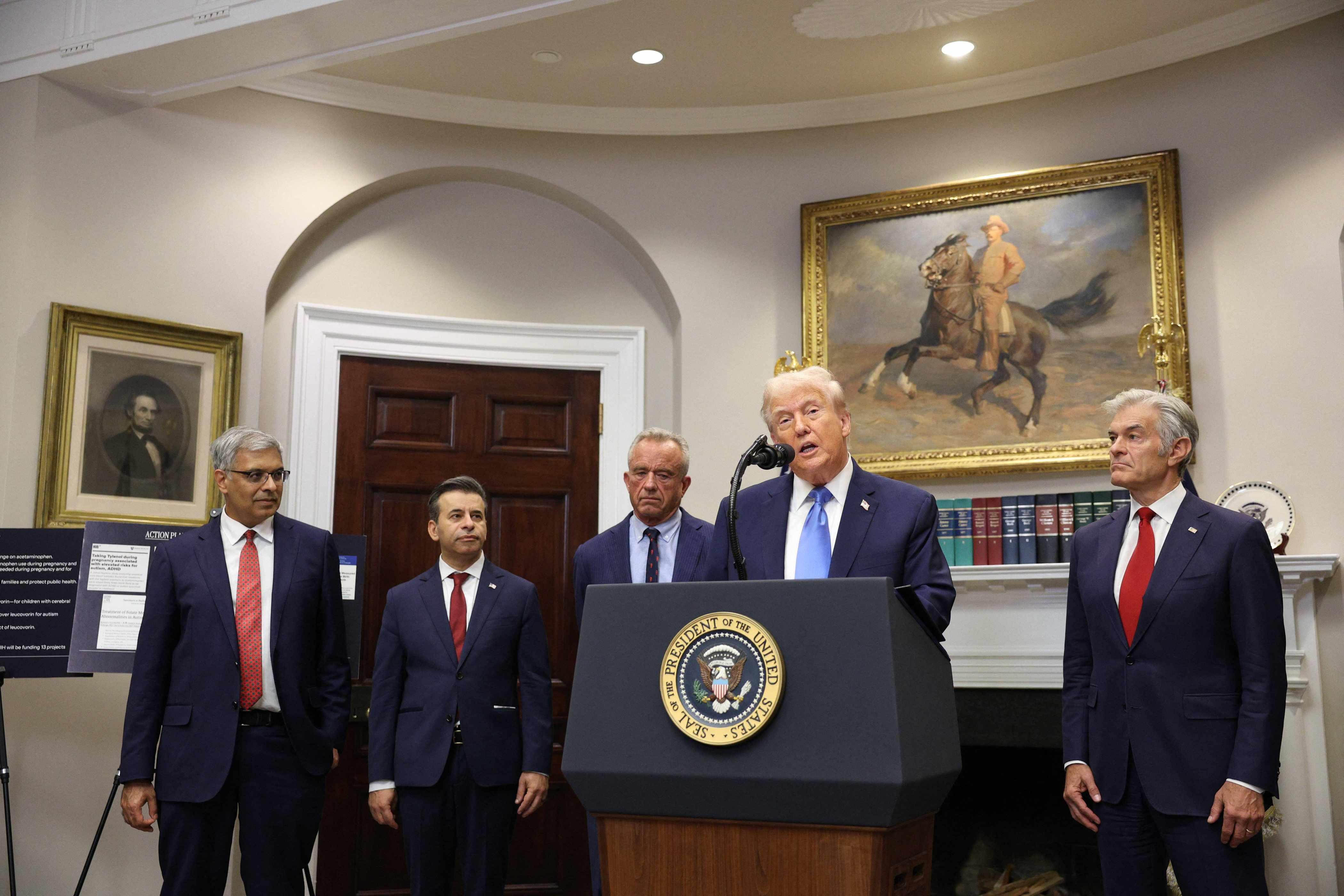 President Donald Trump speaks at a press conference, flanked by administration members, discussing a link between acetaminophen and autism.