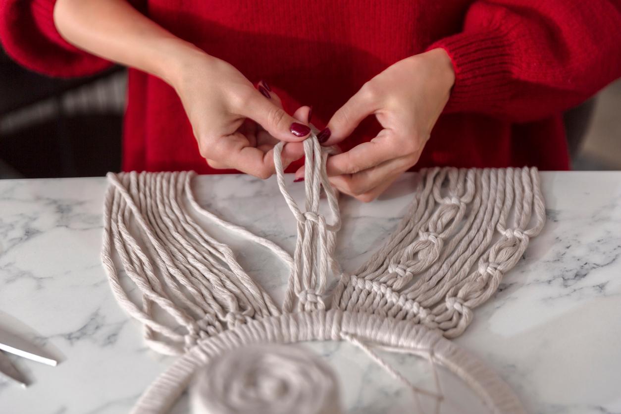 Person moving various macrame cords into place while working on a project.