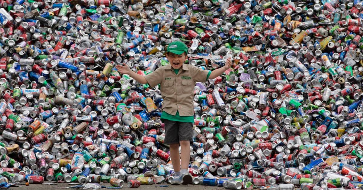 Young boy (6-8) holding an armful of recyclable plastic bottles