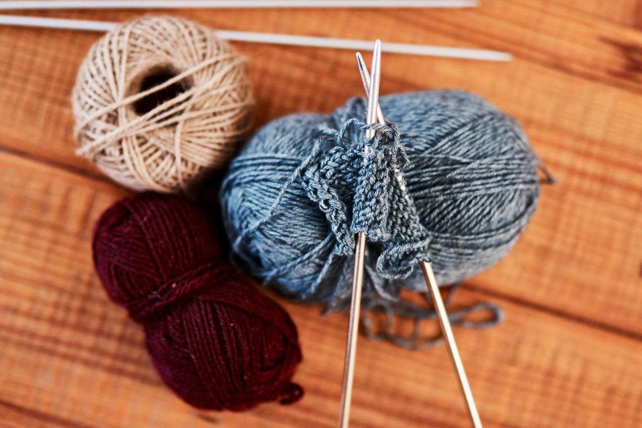 Various colored yarn and a pair of knitting needles on a table.