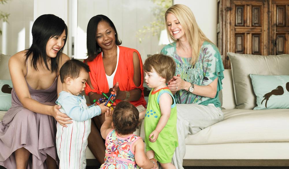 Moms sitting together with their kids.