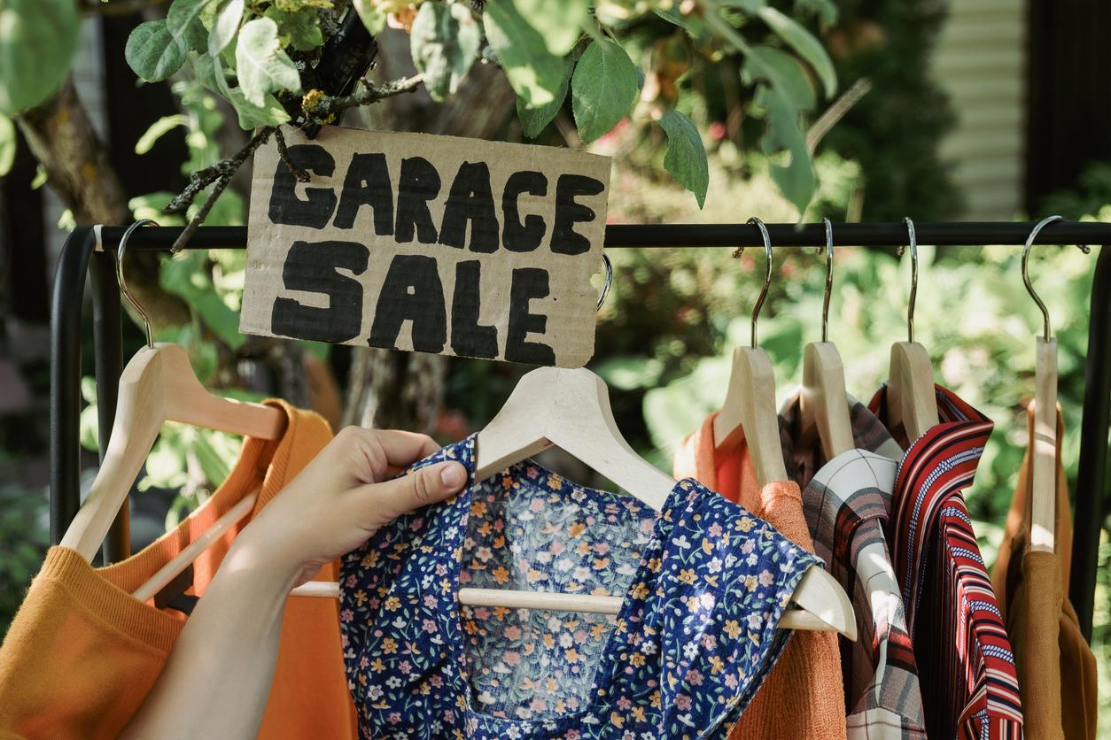 Garage sale sign hovering over a full clothing rack.