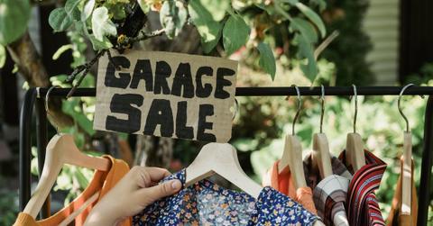 Garage sale sign hovering over a full clothing rack.