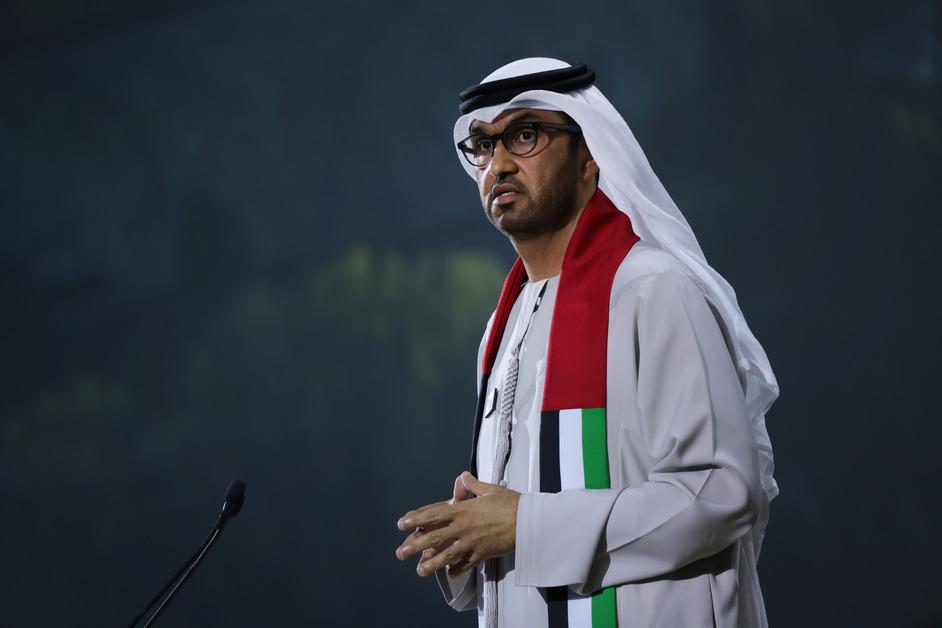 COP28 president Sultan Al Jaber stands at a podium with a microphone speaking to a crowd at the COP28 conference in Dubai. 