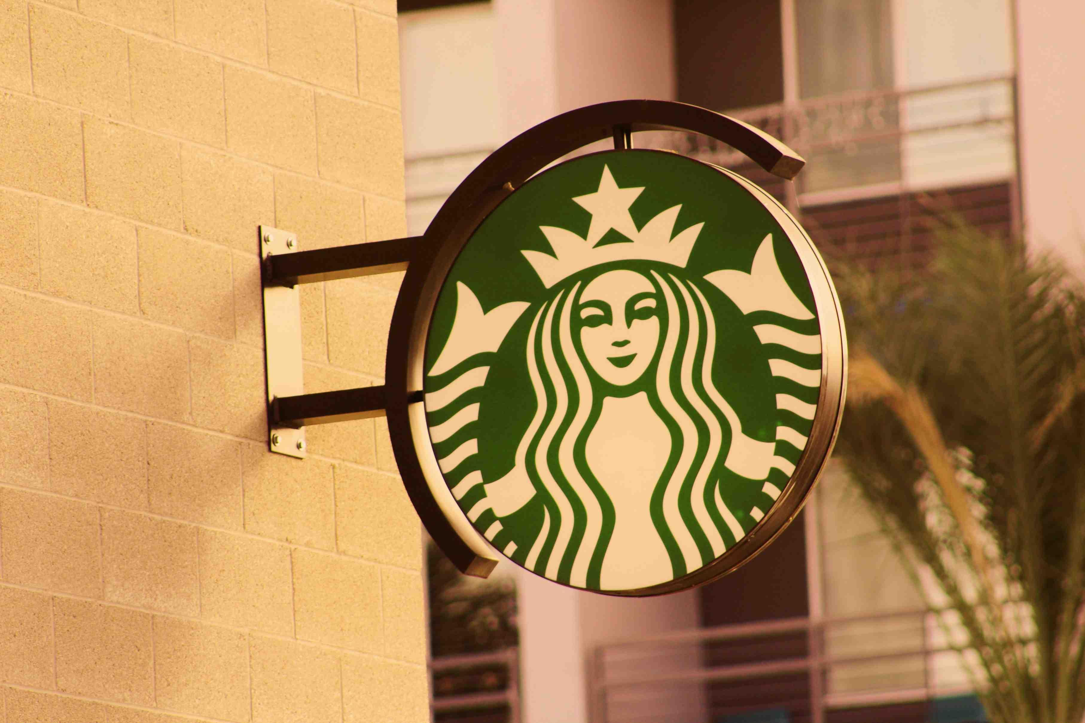A Starbucks sign depicting its logo is pictured affixed to a concrete wall.