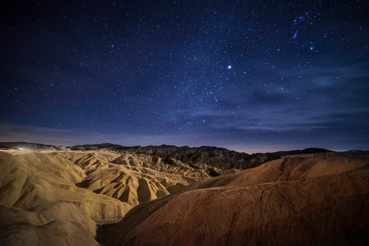 A night sky lit by stars over Death Valley National Park's moutainous landscape