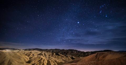A night sky lit by stars over Death Valley National Park's moutainous landscape