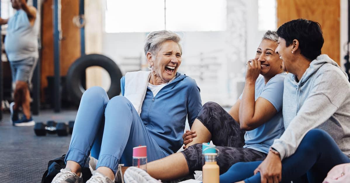 Three friends sitting together on a gym break and lauging