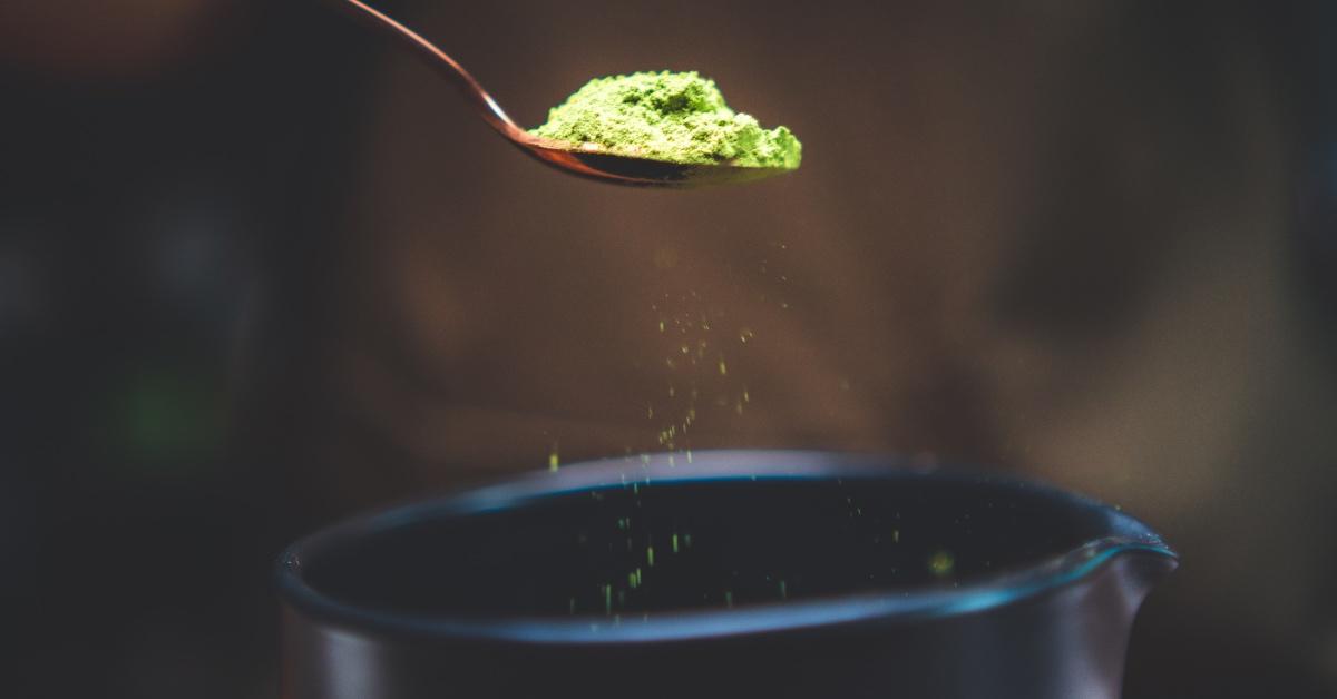 Ceremonial grade green tea being sprinkled into a cup.