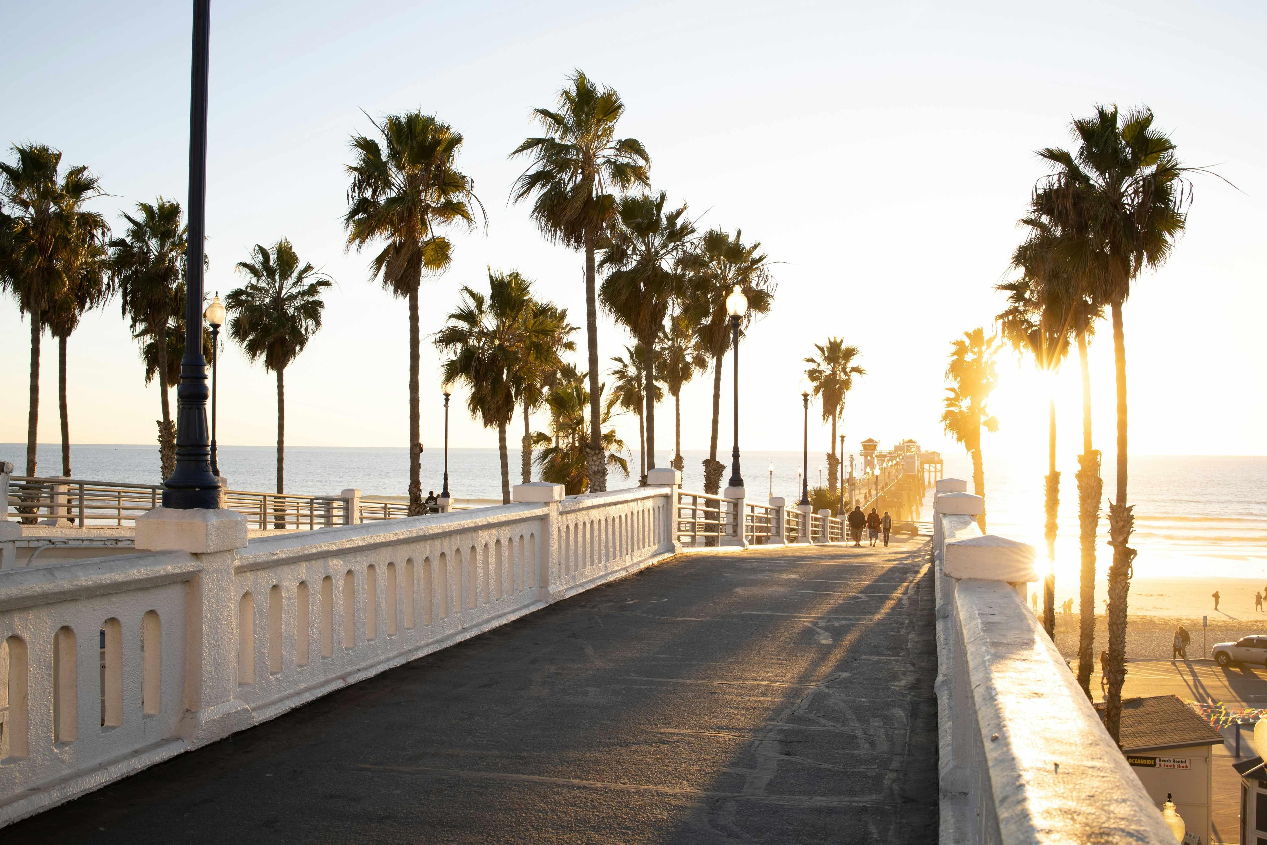 Oceanside Pier in California is pictured as the sun peeks through the trees.