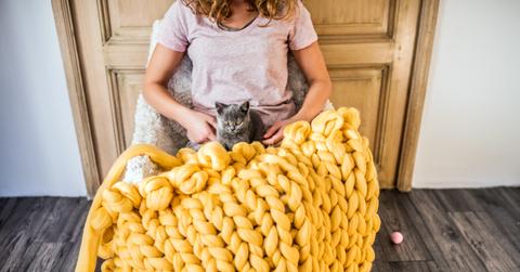 A yellow chunky knit blanket on someone's lap.