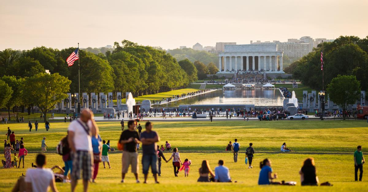 Photo of people on the grass in front of the Lincoln Memorial and Reflecting Pool in Washington, D.C.