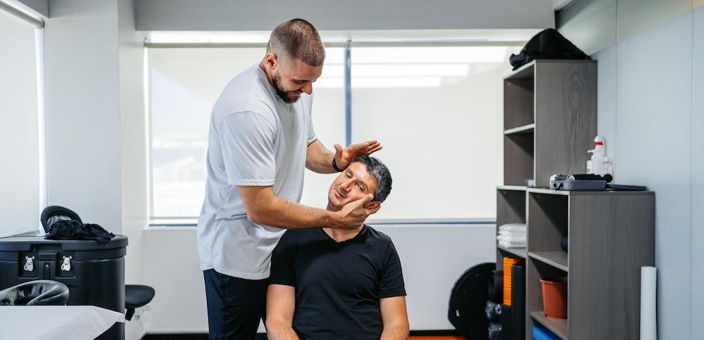 A man getting his neck cracked by a physical therapist. 