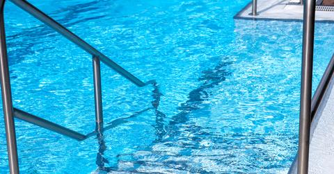 Metal railing and stairs leading into a chlorinated pool.