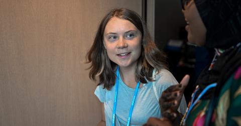 Greta Thunberg smiles and looks at another person