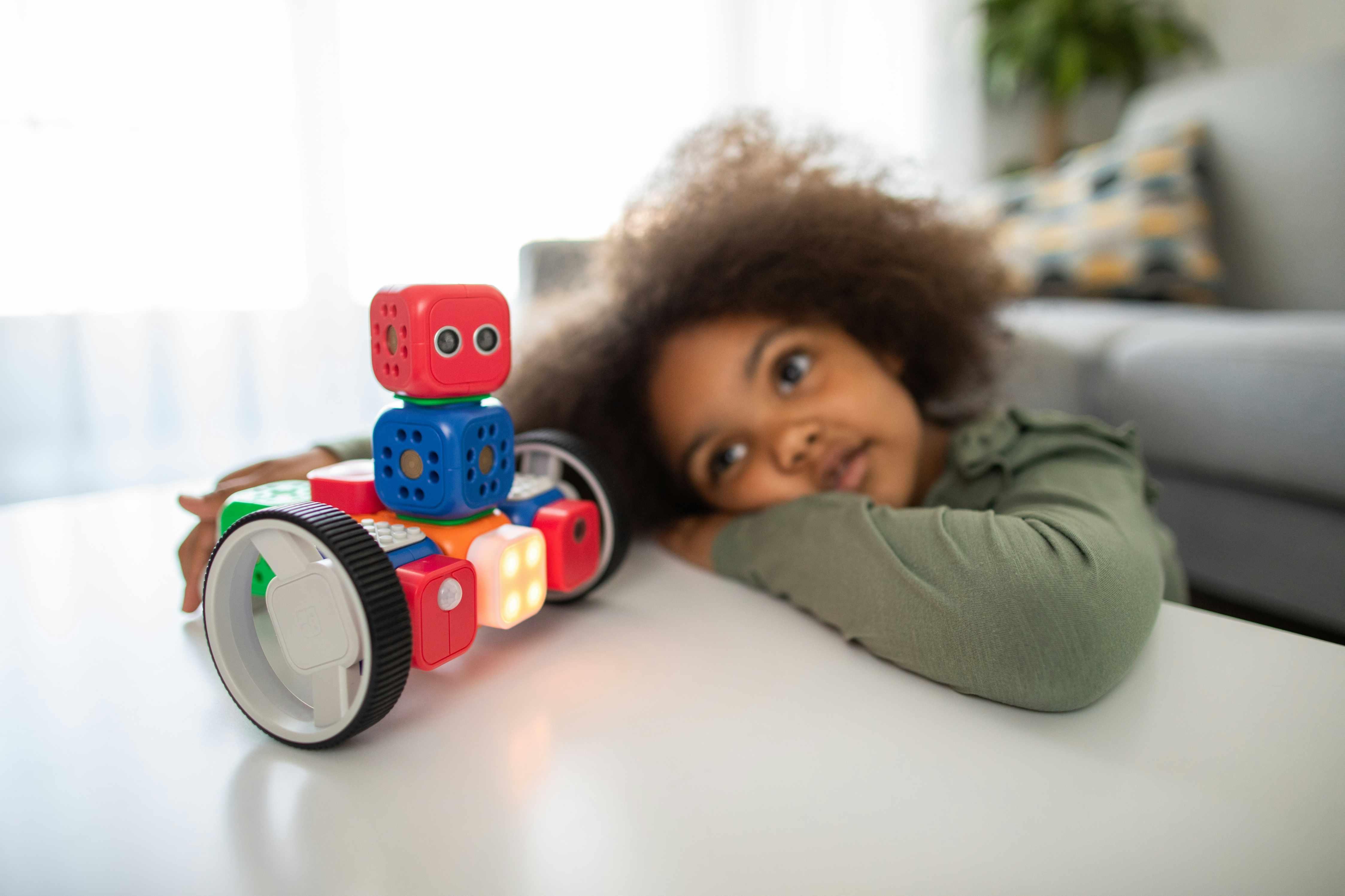 A child with autism lays his head on a table while playing with a stackable robot toy.