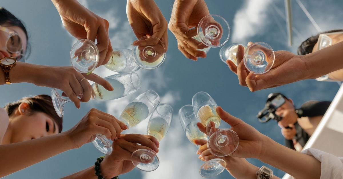 Several people toast with champagne against a blue sky