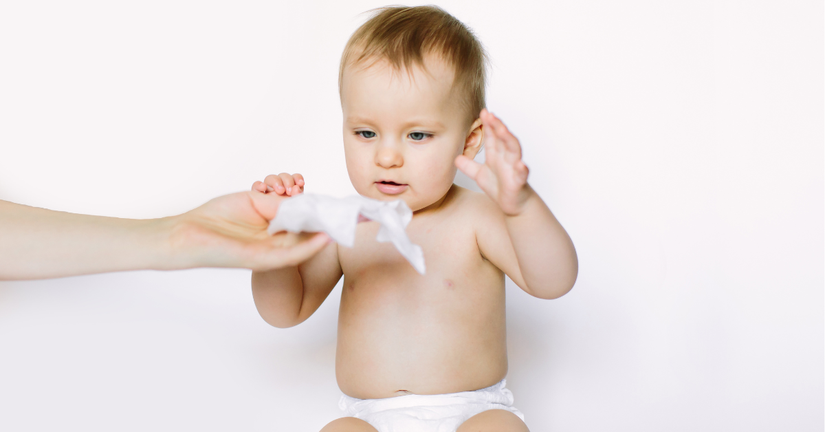 A woman hands a baby a baby wipe