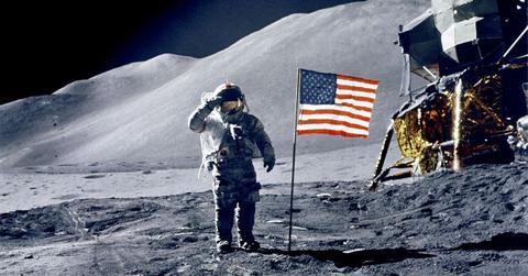 An astronaut on the moon standing next to an American flag. (Representative Cover Image Source: Getty Images | Michael Dunning)