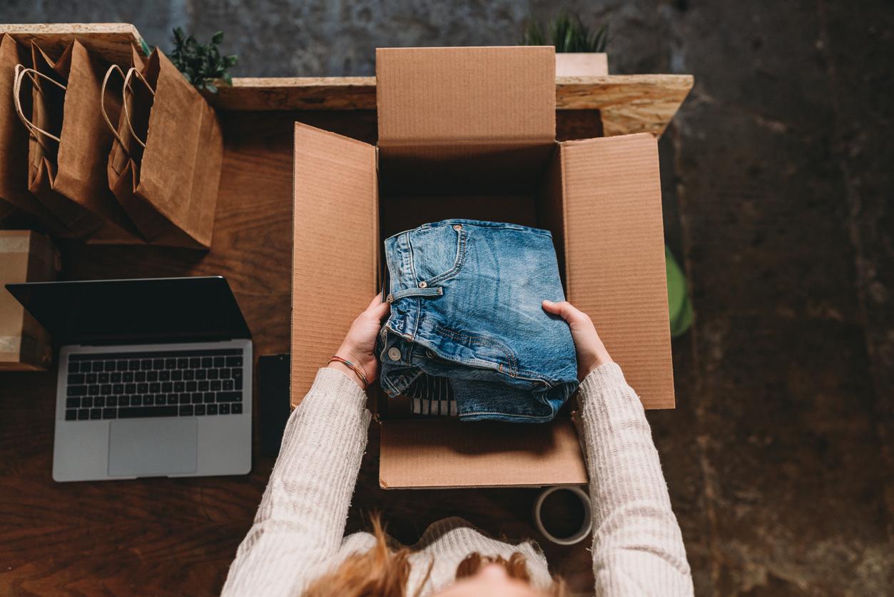 Person putting old jeans into box.