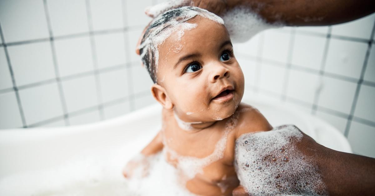 Man washing hair of adorable baby in bathtub