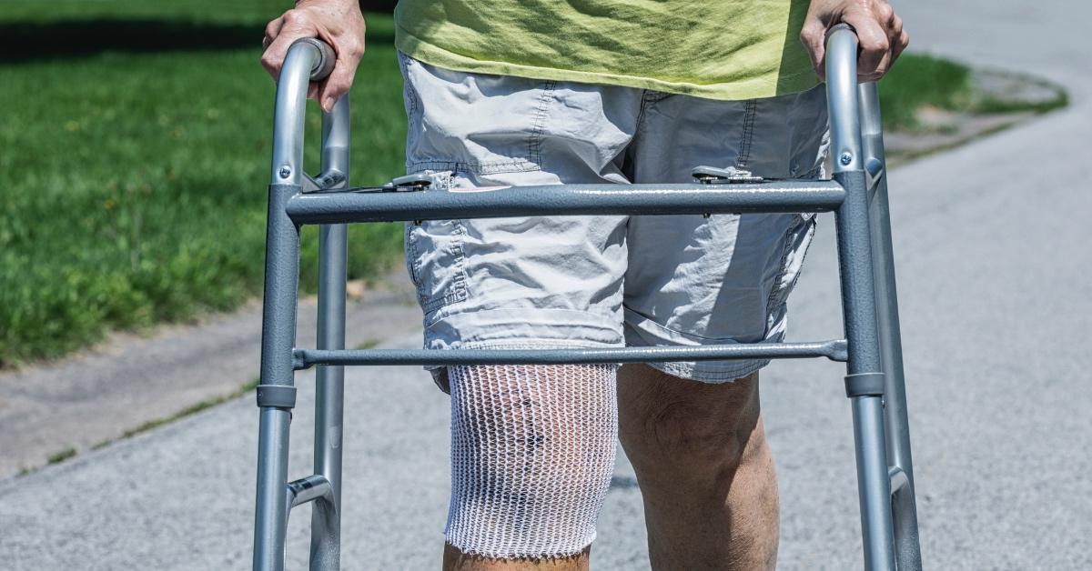 Person after knee surgery using a walker to walk.